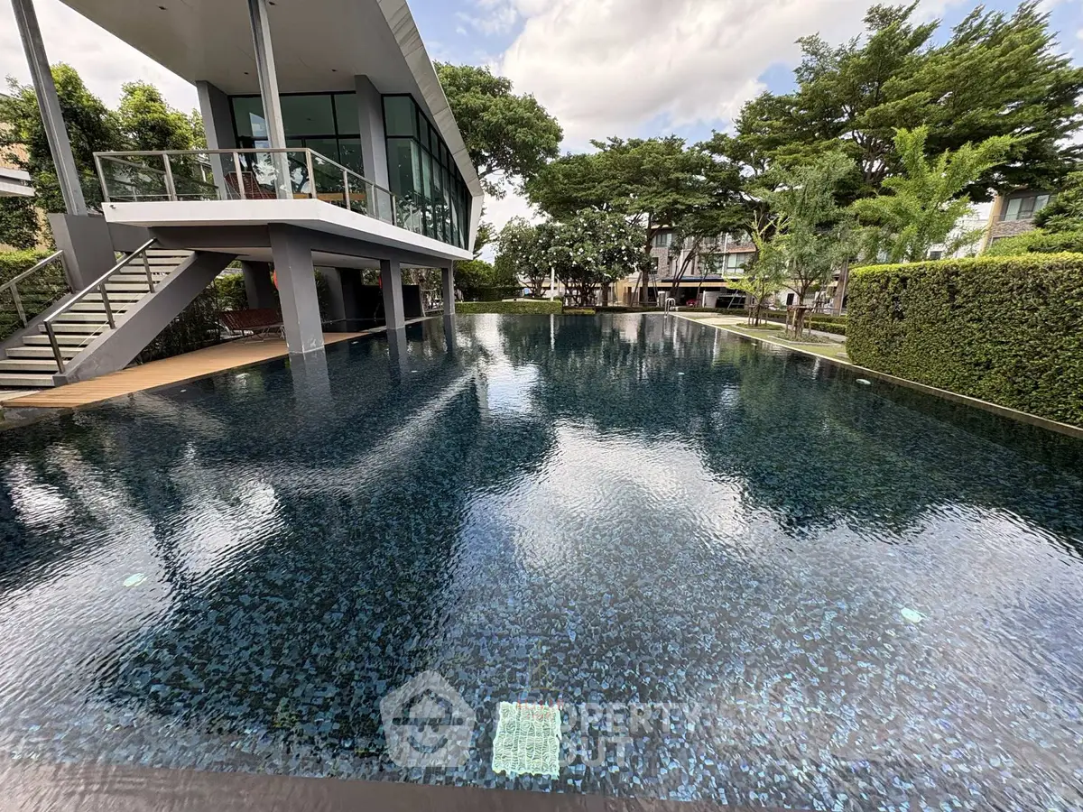 Luxurious modern poolside view with lush greenery and contemporary architecture.