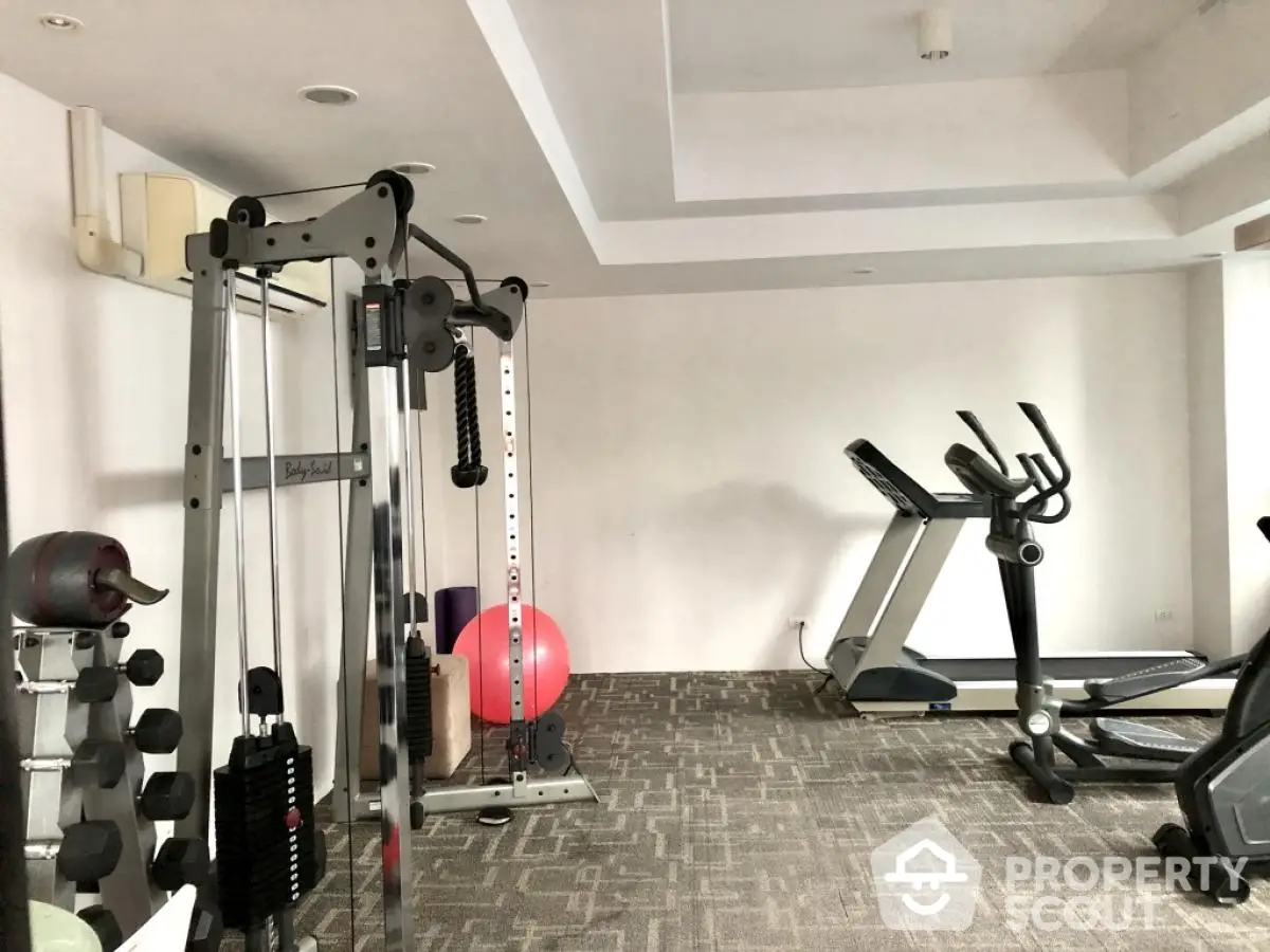 Modern home gym with exercise equipment and carpet flooring