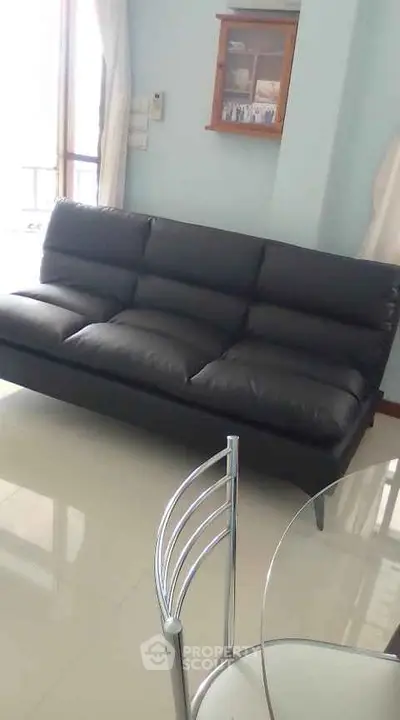 Modern living room with sleek black leather sofa and glass dining table, perfect for stylish urban living.