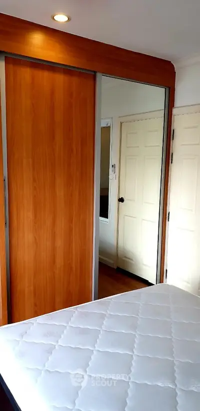 Cozy bedroom with wooden wardrobe and comfortable mattress, perfect for restful nights.