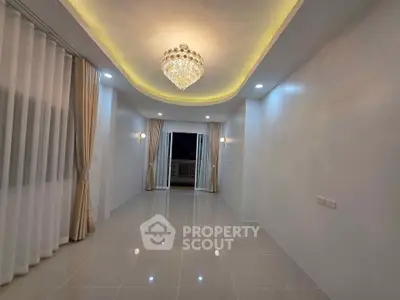 Elegant living room with chandelier and balcony access, featuring modern lighting and glossy tiled floors.