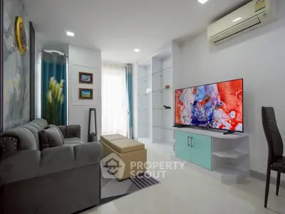 Modern living room with stylish decor, large TV, and comfortable seating in a bright apartment.