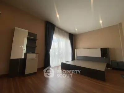 Spacious modern bedroom with large window and elegant wooden flooring.