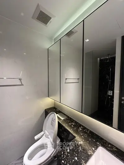 Luxurious modern bathroom with sleek black marble accents and elegant lighting.
