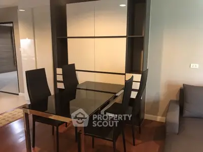 Modern dining area with sleek black table and chairs, adjacent to cozy living space.