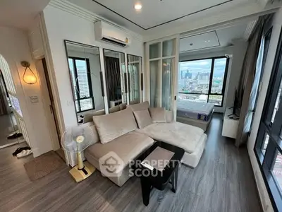 Modern living room with city view, featuring stylish furniture and large windows.