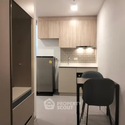 Modern compact kitchen with sleek cabinetry and dining area in cozy apartment