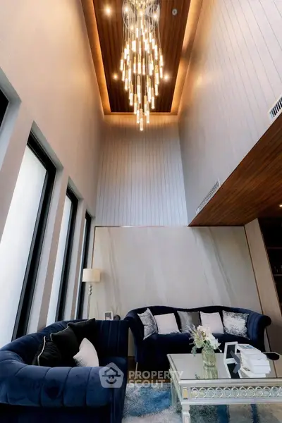 Luxurious high-ceiling living room with elegant chandelier and plush velvet sofas