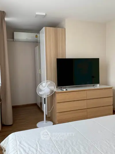 Modern bedroom with sleek furniture and flat-screen TV, perfect for a cozy living space.