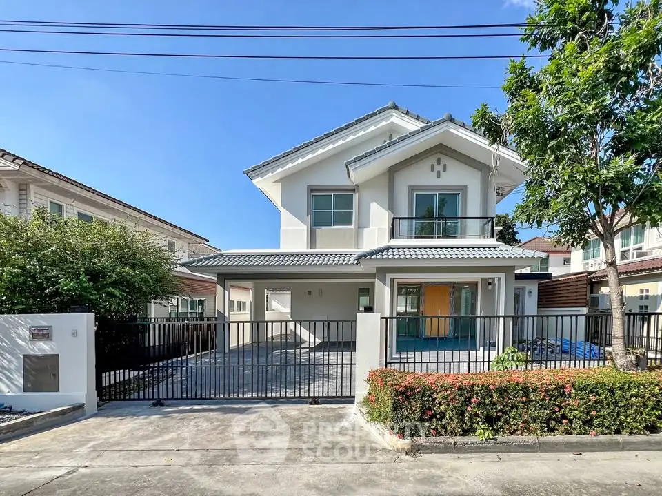Charming two-story house with gated driveway and lush greenery in a serene neighborhood.
