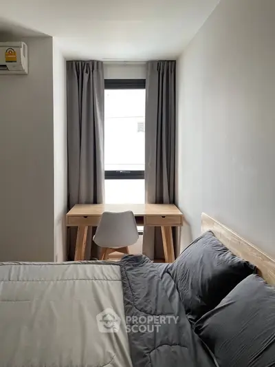 Cozy bedroom with modern decor, featuring a wooden desk by the window and stylish bedding.