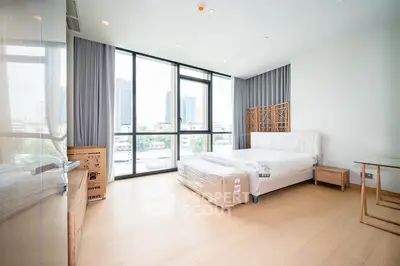 Spacious bedroom with large windows and city view, featuring modern furnishings and natural light.