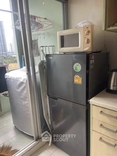 Compact balcony with modern appliances including fridge, microwave, and washing machine, ideal for urban living.