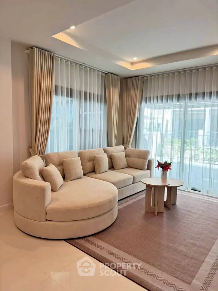 Elegant living room with modern round sofa and large windows, perfect for relaxation and entertaining.
