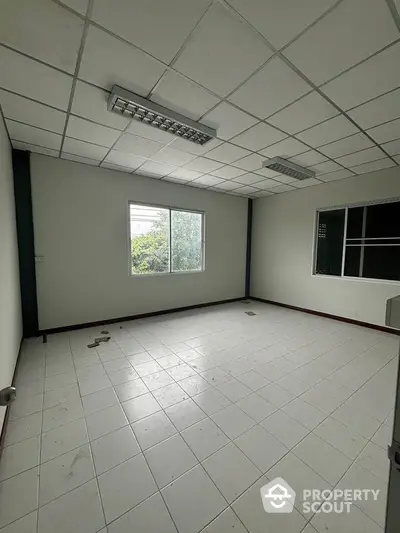 Spacious empty room with large window and tiled flooring, ideal for customization.