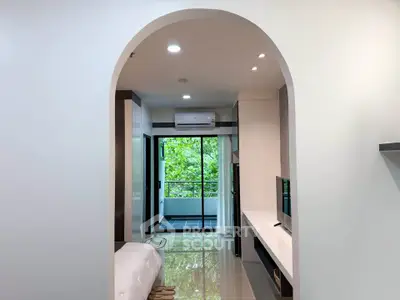 Modern apartment interior with archway, sleek design, and balcony view.