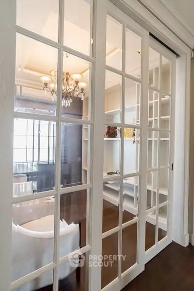 Elegant living room with glass sliding doors and chandelier, showcasing a sophisticated interior design.
