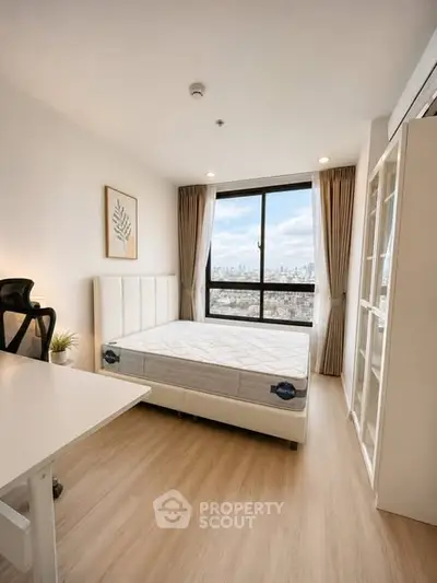 Modern bedroom with city view, featuring a comfortable bed and stylish decor.