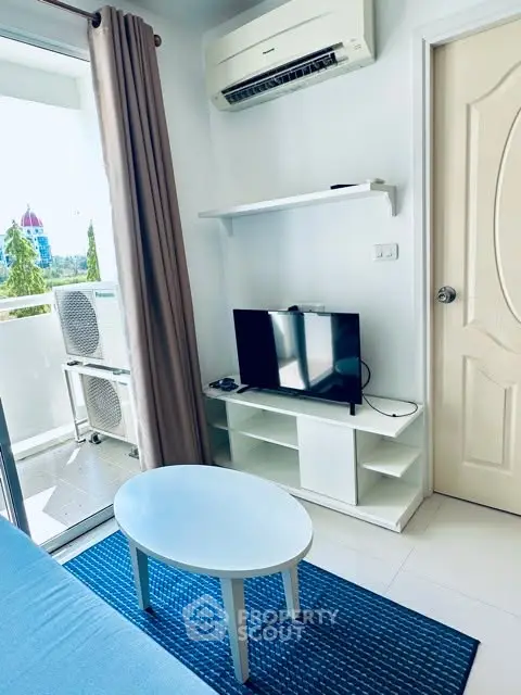 Charming living room with balcony view, featuring modern TV setup and air conditioning.