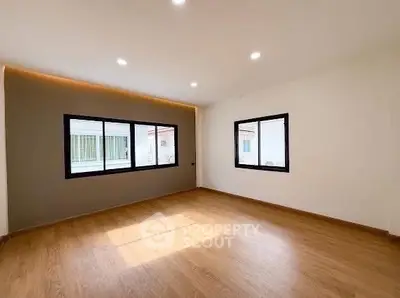 Spacious empty room with large windows and wooden flooring, perfect for customization.