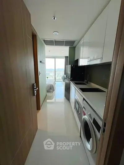 Modern kitchen with sleek appliances and a view of the bedroom and cityscape.