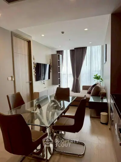 Modern living room with glass dining table and cozy seating area, featuring floor-to-ceiling windows.