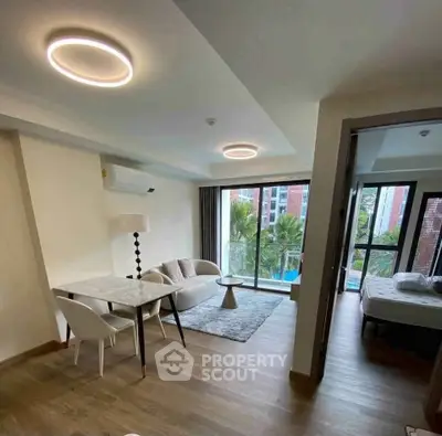 Modern living room with stylish furniture and large windows offering a pool view, perfect for urban living.