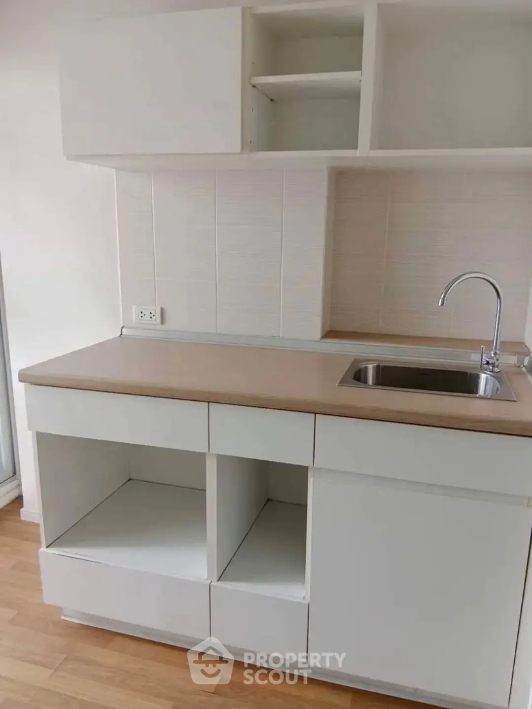 Modern minimalist kitchen with sleek cabinetry and stainless steel sink, perfect for compact living spaces.