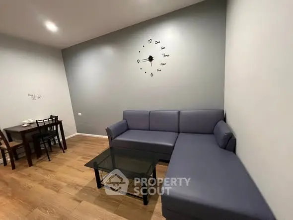 Modern living room with stylish L-shaped sofa and wall clock, perfect for cozy gatherings.