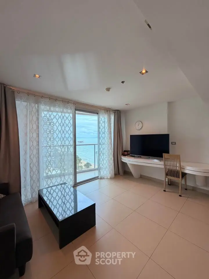 Modern living room with ocean view, sleek furniture, and natural light.