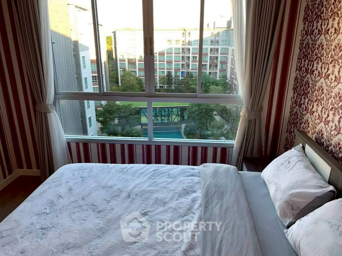 Cozy bedroom with large window offering a stunning city view, perfect for relaxation.