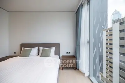 Modern bedroom with large windows offering city views in a high-rise apartment.