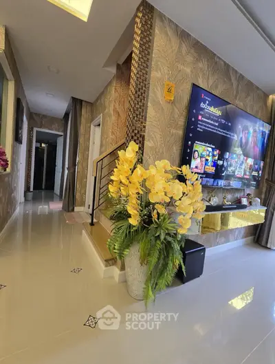 Modern living room with large TV, elegant decor, and indoor plants enhancing the cozy ambiance.