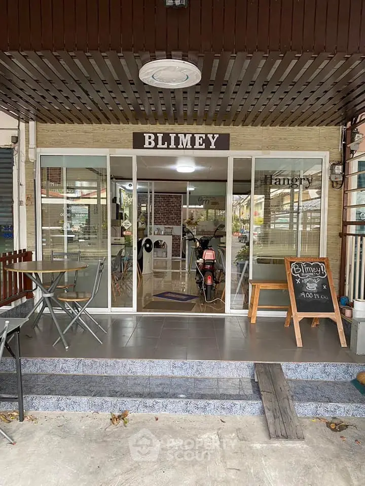 Charming cafe entrance with glass doors and outdoor seating in a cozy neighborhood.