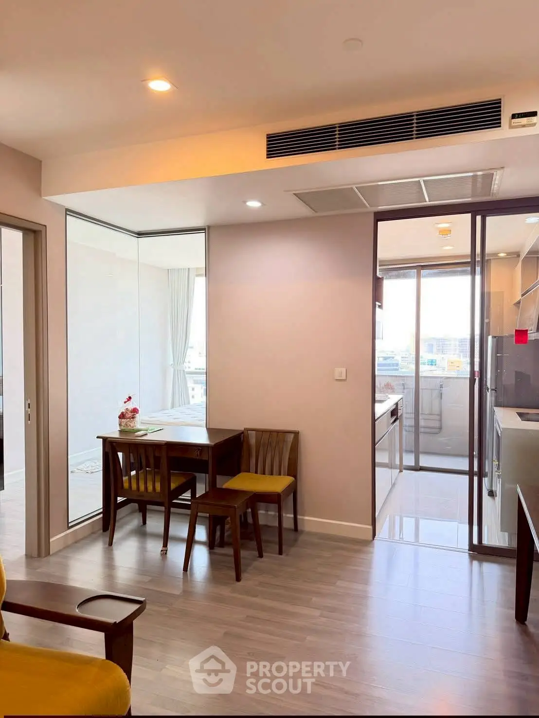 Modern apartment interior with open layout and dining area, featuring sleek kitchen design and large windows.