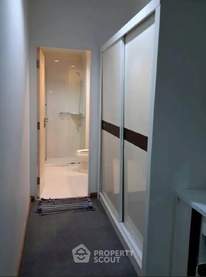 Compact bathroom with sliding door and modern fixtures in a narrow hallway.