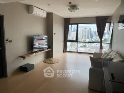 Spacious living room with city view, modern decor, and large windows in urban apartment.