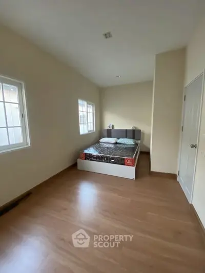 Spacious bedroom with wooden flooring and natural light