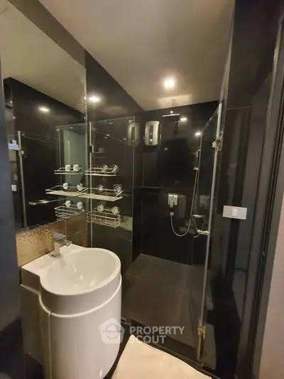 Modern bathroom with sleek black tiles and glass shower enclosure