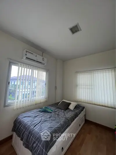 Cozy bedroom with natural light and modern air conditioning unit, perfect for relaxation.