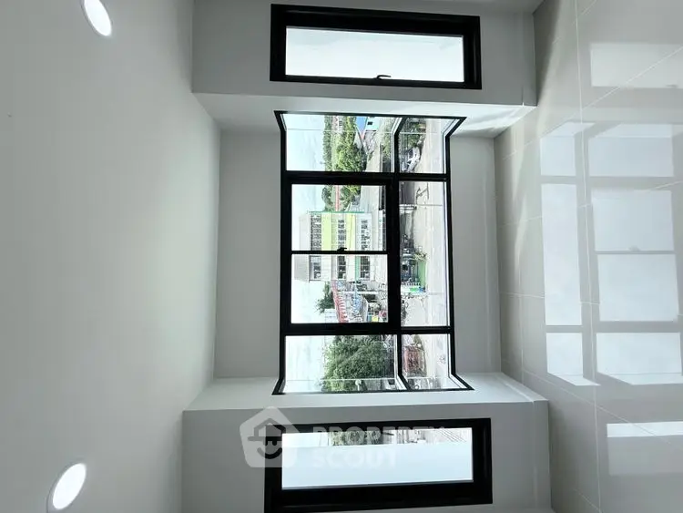 Spacious room with large windows offering a stunning city view, perfect for modern living.