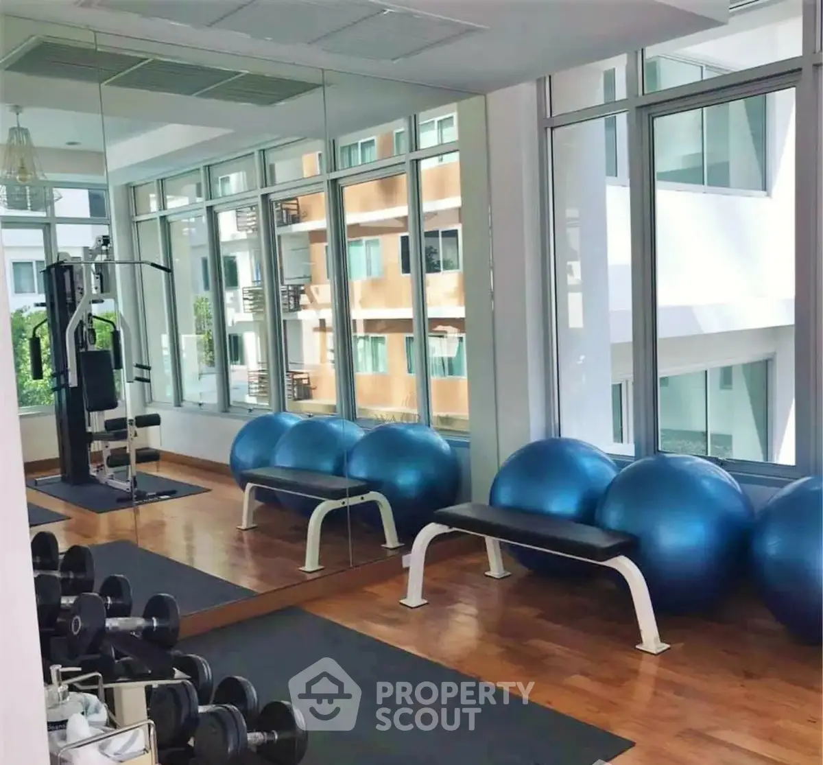 Modern gym with exercise equipment and large windows in a residential building.