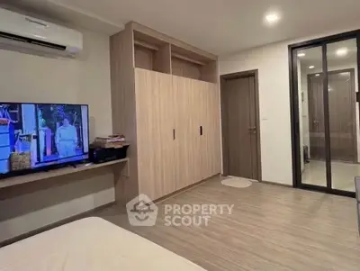 Modern bedroom with built-in wardrobe and wall-mounted TV in stylish apartment.