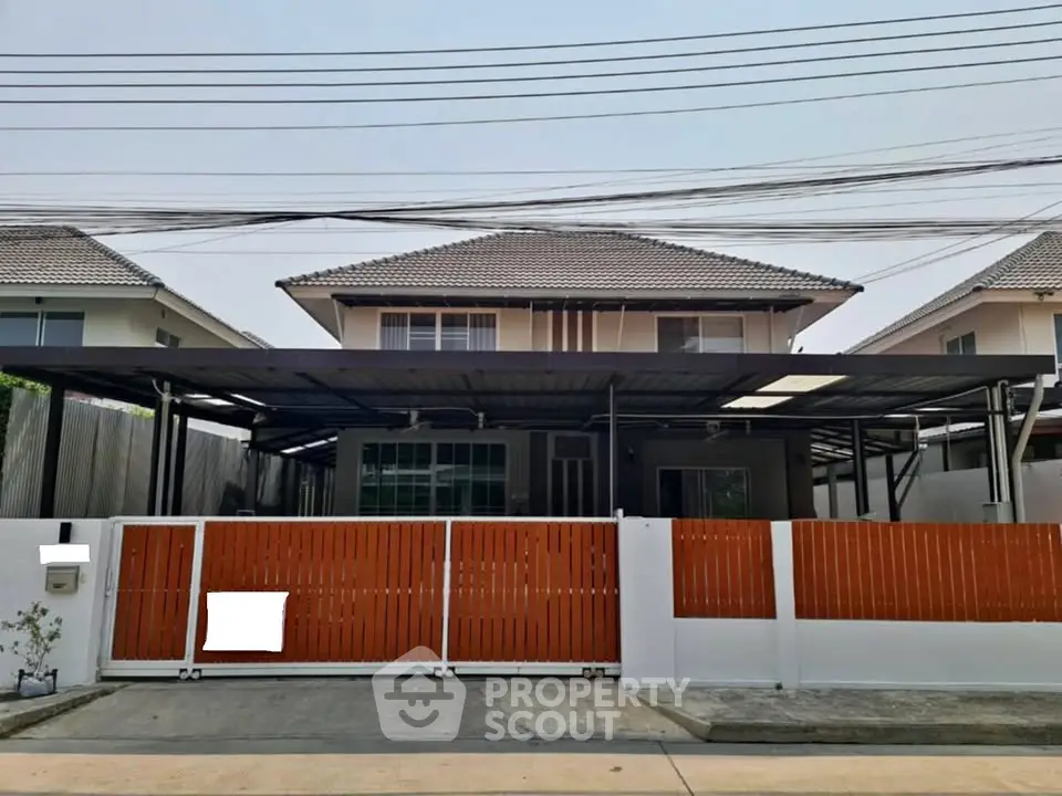 Modern two-story house with gated entrance and carport in suburban neighborhood.