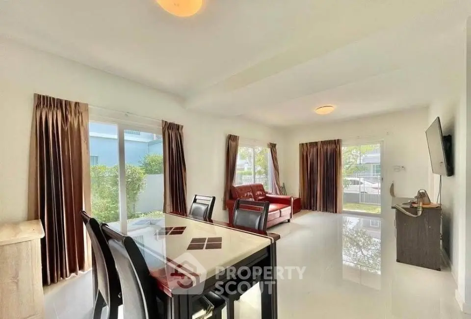 Spacious living room with modern furniture and large windows offering natural light and garden views.