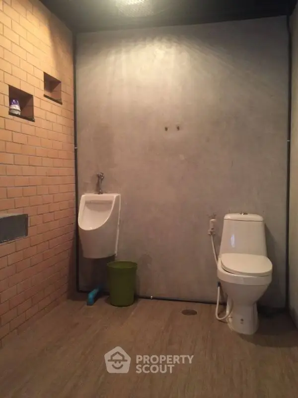 Modern industrial-style bathroom with brick and concrete walls.