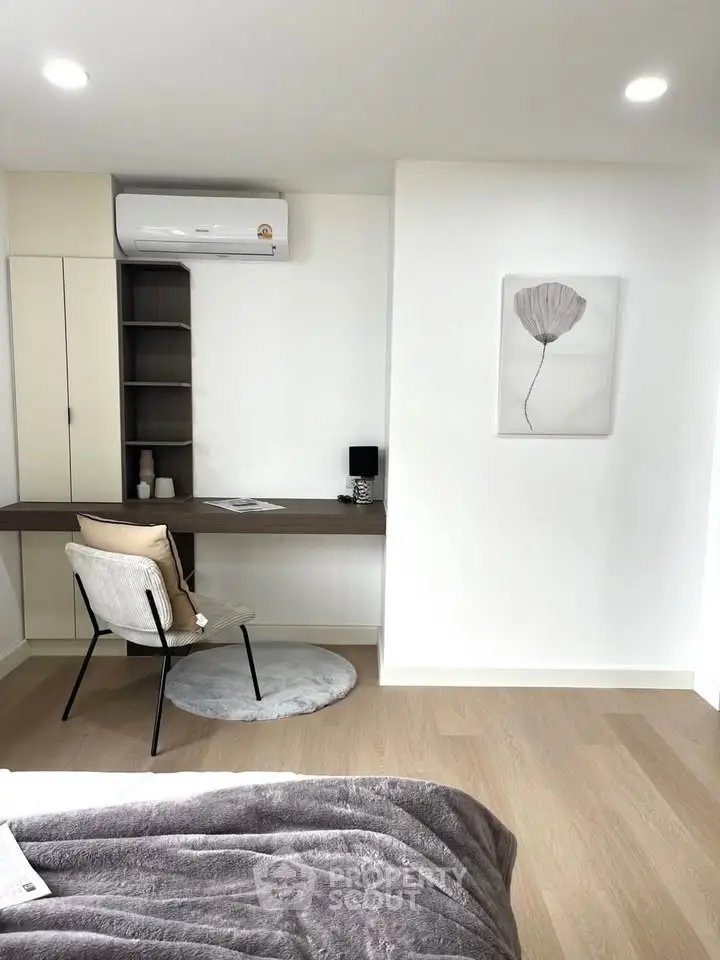 Modern bedroom with study area, featuring sleek desk and cozy chair under air conditioning.