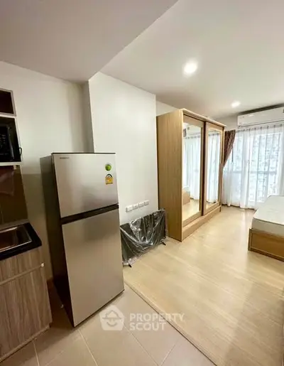 Modern studio apartment with sleek kitchen and spacious bedroom area, featuring large windows for natural light.