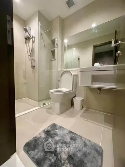 Modern bathroom with sleek design, featuring a glass shower enclosure and contemporary fixtures.