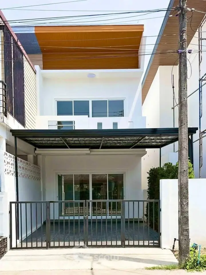 Modern two-story townhouse with gated entrance and sleek design.
